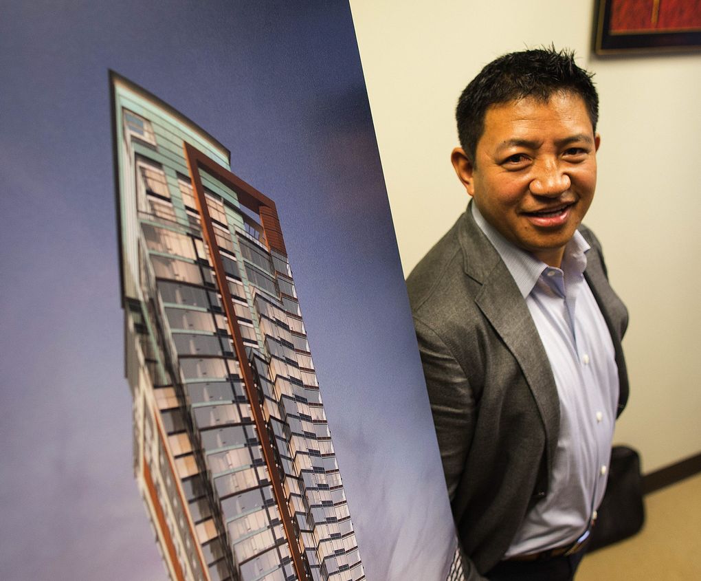 Lobsang Dargey, chief executive of Dargey Development and Path America, stands next to a drawing of one of his planned projects in his Bellevue office.  (John Lok / The Seattle Times)