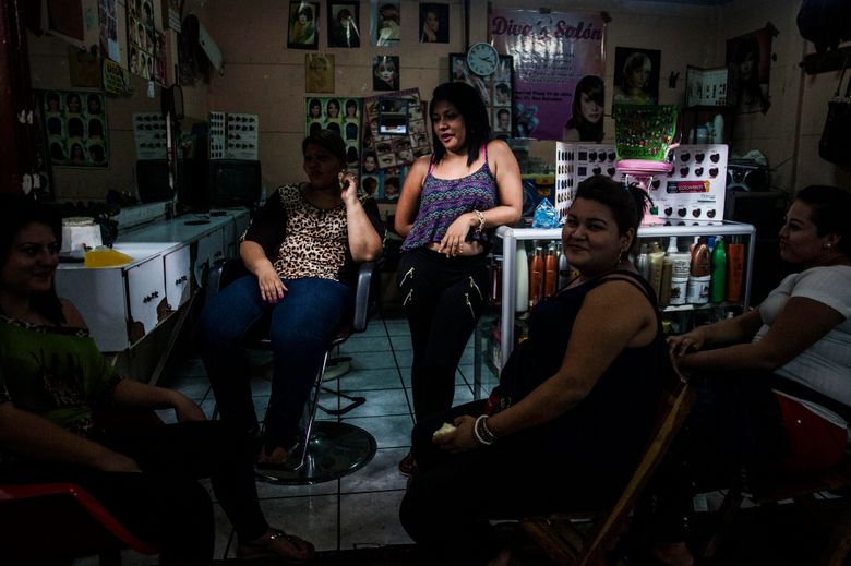 In this June 12, 2015 photo, hairdressers take a break from their work at a hair salon in downtown San Salvador, El Salvador. Violence in El Salvador is reaching a level that rivals the worst days of guerrilla warfare decades ago, few are willing to risk becoming a target. Word on the street is that only the girlfriends of gang members are allowed to be redheads or blondes. So in this violent place, women are scurrying to salons to give up their blond hair and highlights, to dye it all black, not out of fashion sense, but out of fear. (AP Photo/Manu Brabo)