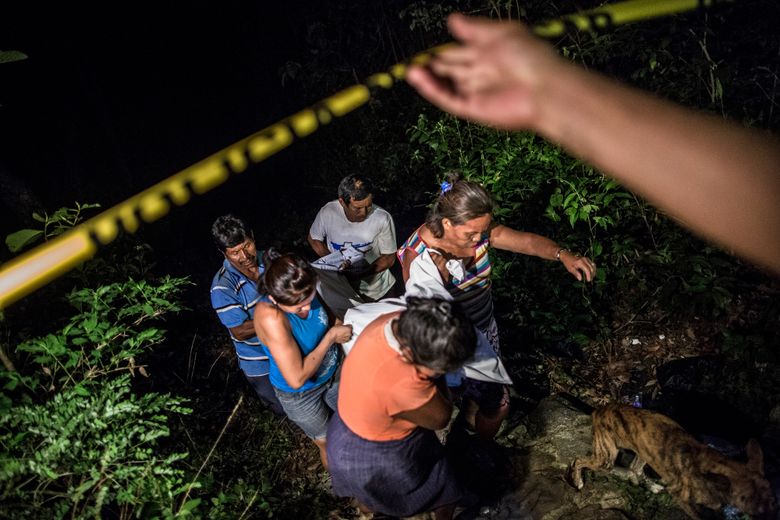In this May 27, 2015 photo, relatives of a Mara Salvatrucha gang member retrieve his body from a steep gully after he was shot dead in a confrontation with police, in Olocuilta, El Salvador. Two bodies were found at the bottom of the gully following a shootout that began near an old cattle stable, which gang members had turned into a shooting range. (AP Photo/Manu Brabo)