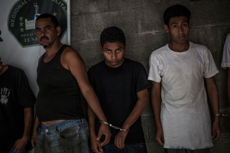 In this May 28, 2015 photo, suspected members of the 18th Street gang stand handcuffed in pairs at a police station in Panchimalco, near San Salvador, El Salvador. A new government announced officially an end to the 2013 gang truce in January, returning leaders to maximum security and starting aggressive attacks and arrests, leaving the streets to younger and more reckless criminals. (AP Photo/Manu Brabo)