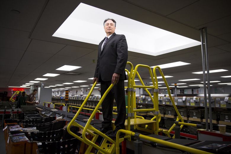 Salvatore Magaddino, the deputy director of BookOps in New York City, stands atop the machine that sorts and dispatches books to city public libraries. (DAMON WINTER/NYT)