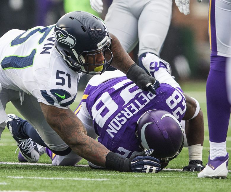 Bruce Irvin drops Adrian Peterson for a 1-yard loss in the first quarter. (Dean Rutz / The Seattle Times)