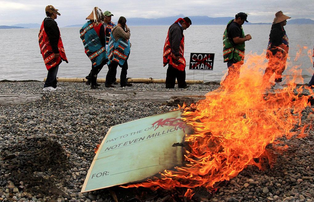 Although accepting a $400,000 check from SSA Marine in 2011 to help with a techincal review of the project proposal, Lummi tribal members burn a symbolic check at Cherry Point in 2012 expressing the tribe’s opposition to coal trains and development at these ancestral grounds. (Alan Berner/The Seattle Times)