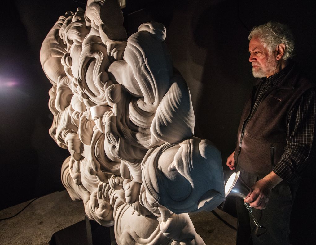 Richard Berger holds a light to the back of a Fontainebleau sandstone concretion, one of many he has in the collection.  (Steve Ringman / The Seattle Times)