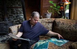 John Reed, studies aerial maps of the Highway 530 Oso mudslide, as he explains what he saw on that the day it occurred, March 22nd, at his home in Oso, on Friday, May 23, 2014.