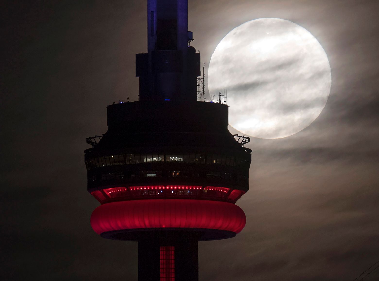 The supermoon sets behind the CN tower in Toronto on Monday, Nov. 14, 2016. The brightest moon in almost 69 years lights up the sky this week in a treat for star watchers around the globe. (Frank Gunn/The Canadian Press via AP)