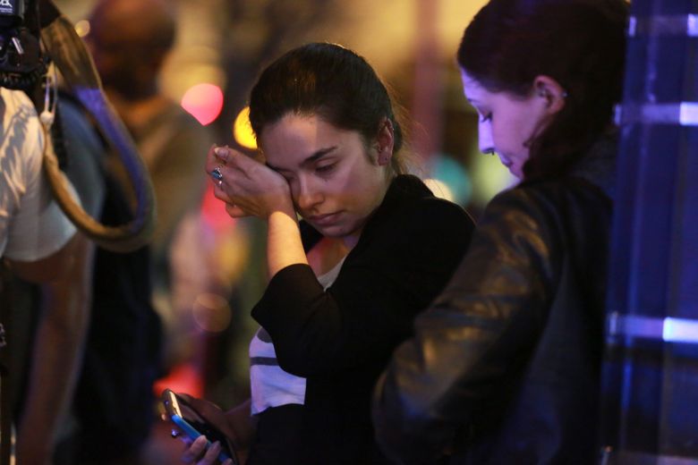 A woman wipes her eye near the site of a multiple shooting near Third and Pike in downtown Seattle.