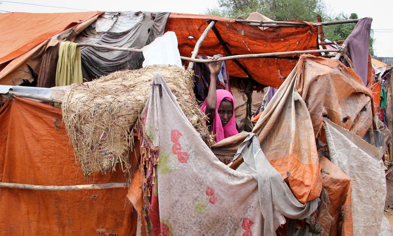 In this photo taken Wednesday, Nov. 16, 2016, Somali refugee and mother of six Madino Dhurow, who was repatriated to Somalia from Kenya’s Dadaab camp, stands by her makeshift shelter in the Daryeel camp for the displaced, where she now lives in Mogadishu, Somalia. (AP Photo/Farah Abdi Warsameh)