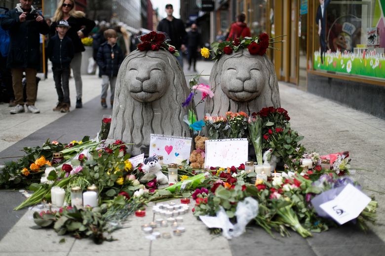 Flowers and candles are placed around stone lions near the department store Ahlens following a suspected terror attack in central Stockholm Sweden Saturday