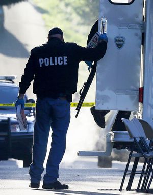 A police officer collecting evidence at the shooting scene carries a shotgun, a dictionary and a copy of a book, “Fight Back and Win: What to Do When You Feel Cheated or Wronged.” 