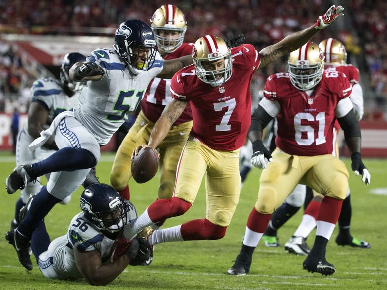 Seahawks defensive lineman Cliff Avril wraps up 49ers quarterback Colin Kaepernick’s feet as Seahawks linebacker Bruce Irvin closes in in the second quarter. (Bettina Hansen / The Seattle Times)