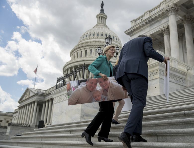 Senate Minority Leader Sen. Chuck Schumer of N.Y., right, and Sen. Elizabeth Warren, D-Mass., carry photographs of their constituents who would be adversely affected by the proposed Republican Senate health-care bill after speaking to reporters outside the Capitol Building in Washington, on Tuesday. (Andrew Harnik / AP) 