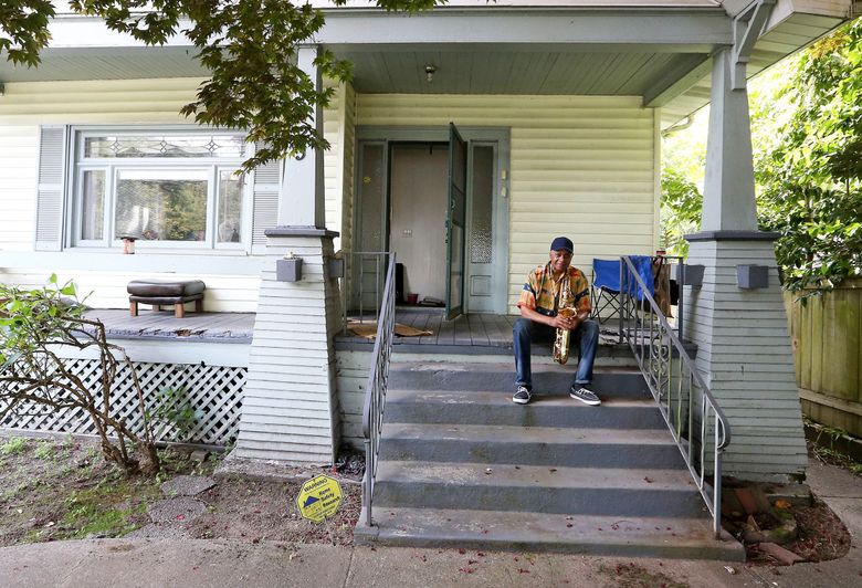 Musician Gary Hammon plays his tenor sax outside his home in the Central District, which his parents purchased in the 1950s. “It was a big deal” when they bought the house, Hammon says. But stories like the Hammons’ are a lot less common these days. (Greg Gilbert/The Seattle Times)
