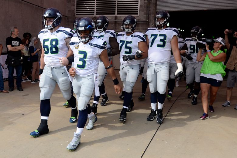 Seattle Seahawks quarterback Russell Wilson (3) and center Justin Britt (68) walk to the field with arms linked after the national anthem had been played before an NFL football game between the Seahawks and the Tennessee Titans Sunday, Sept. 24, 2017, in Nashville, Tenn. Neither team was present on the field for the playing of the anthem. (AP Photo/Mark Zaleski)