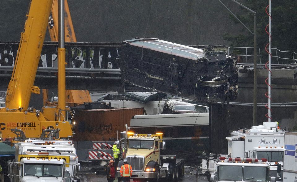 A damaged Amtrak train car is lowered from an overpass at the scene of Monday's deadly train crash onto Interstate 5 at DuPont. — Photograph: Elaine Thompson/The Associated Press.