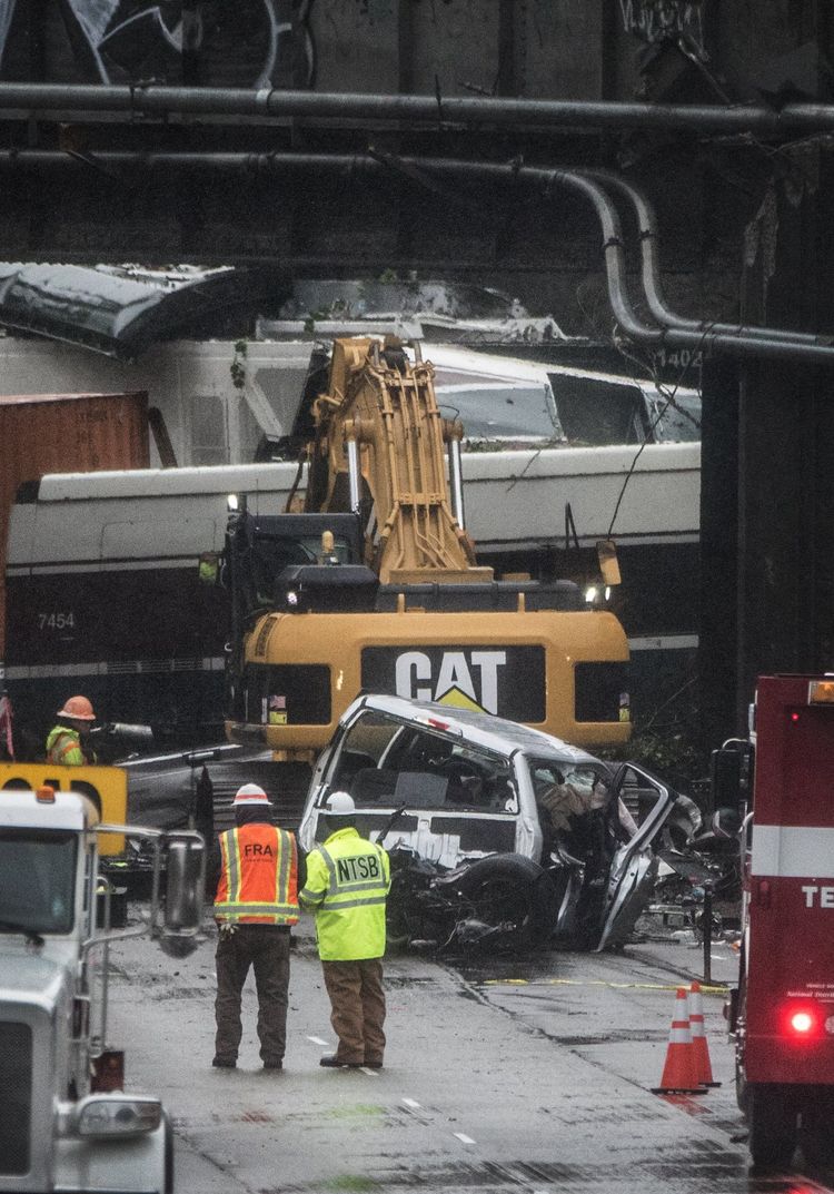 An NTSB investigator looks over the crumpled vehicle pulled from under the Amtrak bridge on Tuesday at the site of the fatal train derailment near DuPont. — Photograph: Steve Ringman/The Seattle Times.