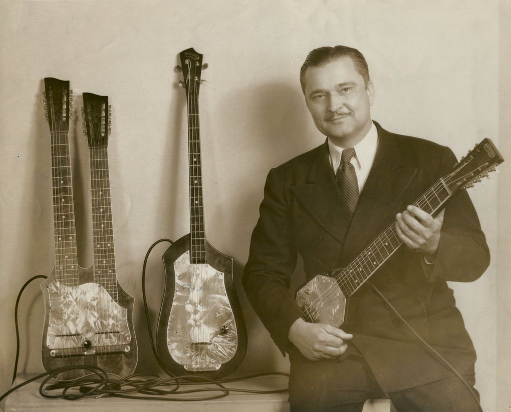 Paul Tutmarc with three of the guitars he made.  On the left is a two neck guitar with 