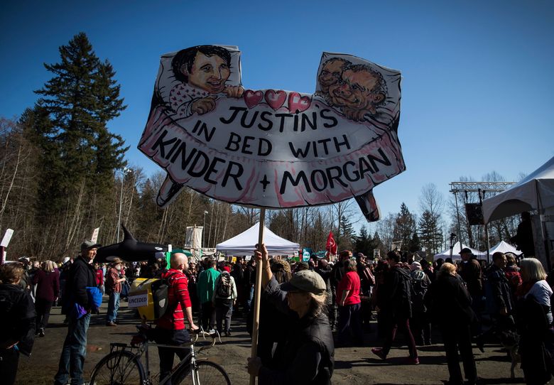 A man carries a sign as thousands of people attend a rally after marching together during a protest against the Kinder Morgan Trans Mountain pipeline expansion in Burnaby, British Columbia, Saturday, March 10, 2018. (Darryl Dyck/The Canadian Press via AP)