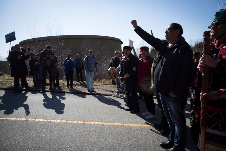Rueben George, project manager for the Tsleil-Waututh Nation Sacred Trust Initiative, raises his fist while stopped near a Kinder Morgan storage tank as thousands of people march together during a protest against the company’s Trans Mountain pipeline expansion in Burnaby, British Columbia, Saturday, March 10, 2018. (Darryl Dyck/The Canadian Press via AP)