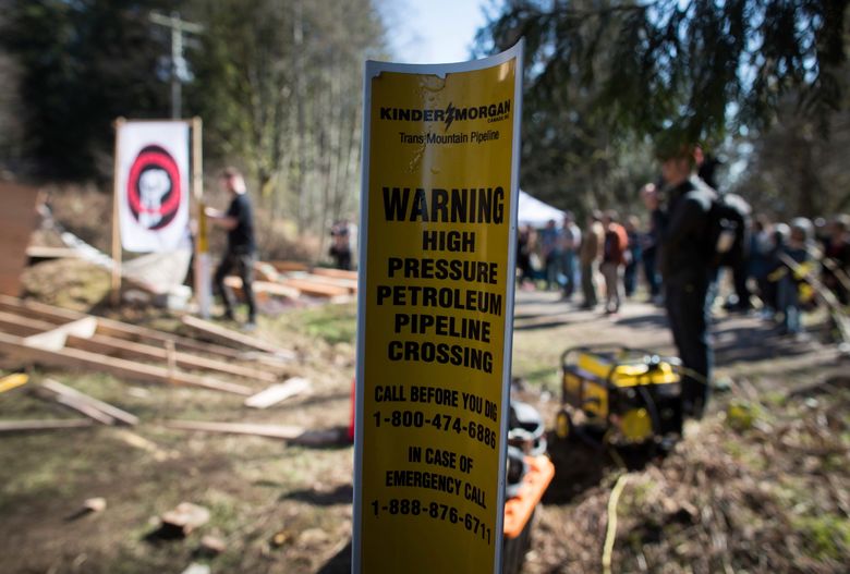 A sign warns of an underground pipeline as people construct a “watch house” near a gate leading to Kinder Morgan’s property during a protest against the company’s Trans Mountain pipeline expansion in Burnaby, British Columbia, Saturday, March 10, 2018. (Darryl Dyck/The Canadian Press via AP)