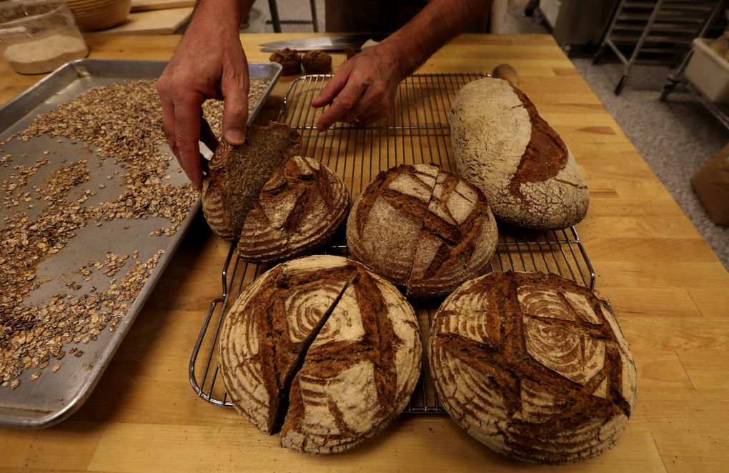 Stephen Jones, founder of the WSU Bread Lab in Burlington, pulls loaves warm from the oven. He has baked the bread with simple ingredients, including 100 percent organic whole wheat, which is freshly milled in the lab on a small stone mill, with high hydration and a long fermentation (sourdough). There are only four ingredients — flour, water, salt, sourdough. Well, also, he says, “love.” (Alan Berner/The Seattle Times)