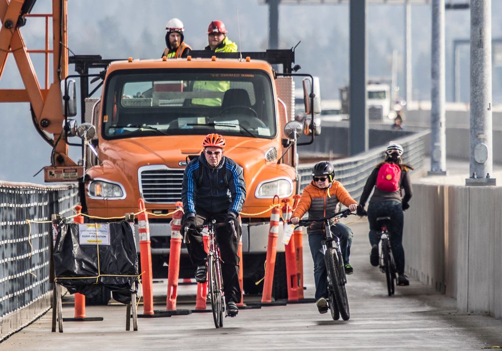 Bicyclists make their way past construction workers on the bridge’s new trail. (Tom Reese)