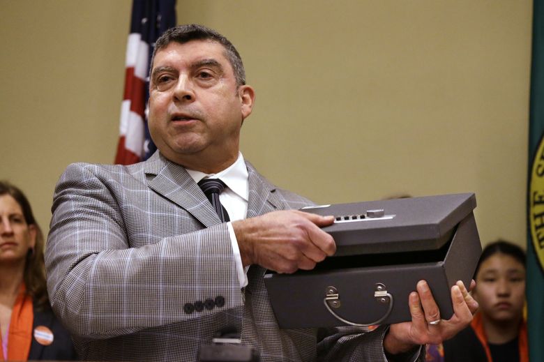 Tony Gomez, Violence and Injury Prevention Manager for Public Health â Seattle & King County, demonstrates the use of a gun lockbox during a news conference. (Elaine Thompson / The Associated Press)