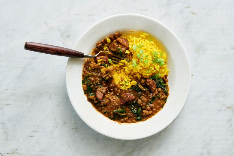   A stew of lentils, chorizo and greens, served with yellow rice, is hearty, filling and delicious no matter when you have it. (David Malosh/The New York Times)