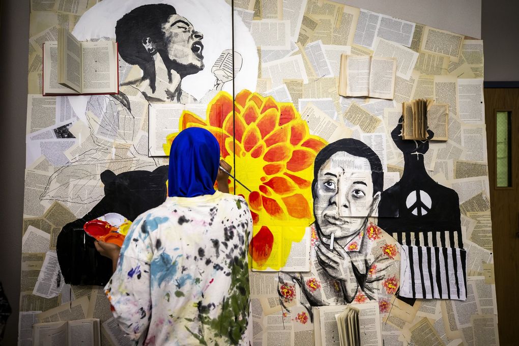 Samira Jimaale, 18, a senior at Franklin High School, paints a mural featuring Billie Holiday and James Baldwin. Students in the school’s Art of Resistance & Resilience club are helping to create set design elements for the upcoming play “Don’t Call it a Riot!” by Seattle playwright Amontaine Aurore. (Bettina Hansen / The Seattle Times)