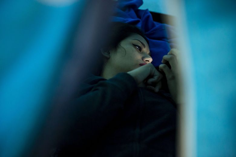 Daniela, 19, checks her cell phone at a shelter in Tijuana, Mexico. Daniela talked about the difficulties that women can face El Salvador, including sexual assault and death threats. Daniela was living in a Tijuana shelter while in the process of applying for U.S. asylum. (Erika Schultz / The Seattle Times)