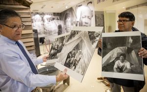 Rogelio Riojas, left, president and CEO of Sea Mar Community Health Centers, and Jerry Garcia, museum vice president, look over historical photos of farmworker tent encampments. (Bettina Hansen / The Seattle Times)