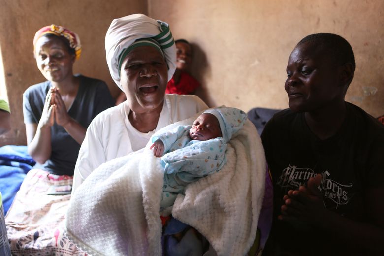 Esther Zinyoro Gwena holds one of the babies she has just delivered in her tiny apartment in the poor suburb of Mbare in Harare, Zimbabwe, Saturday, Nov. 16, 2019.  Grandmother Esther Zinyoro Gwena claims to be guided by the holy spirit and has become a local hero, as the country’s economic crisis forces closure of medical facilities, and mothers-to-be seek out untrained birth attendants.(AP Photo/Tsvangirayi Mukwazhi)