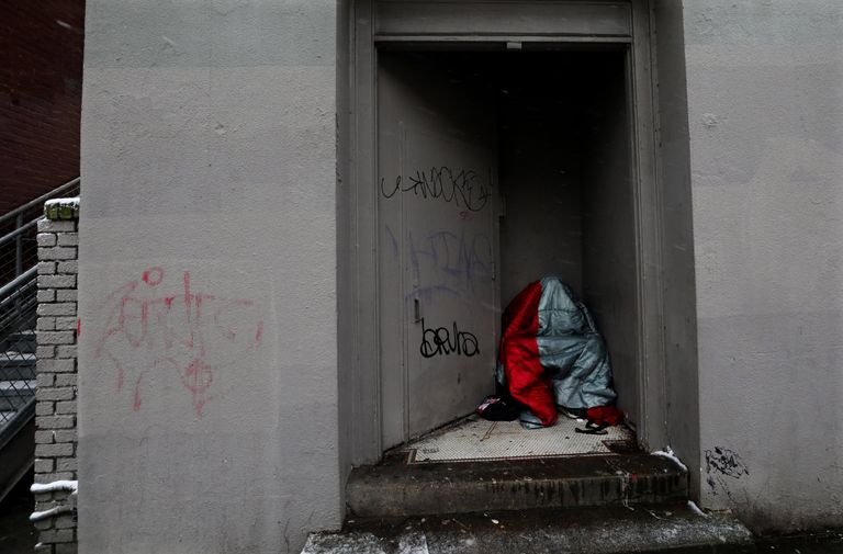A homeless individual huddles under a sleeping bag out of the wind in a Capitol Hill doorway Wednesday afternoon. (Alan Berner / The Seattle Times)