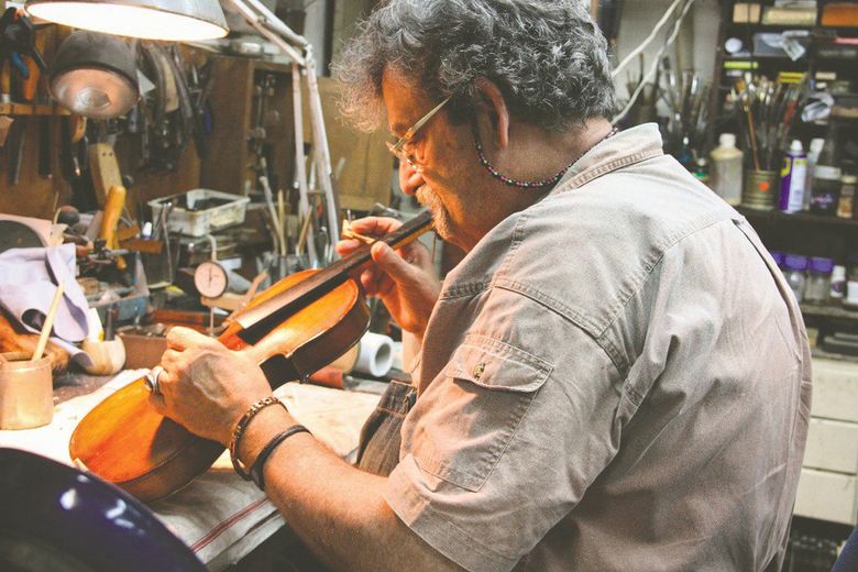 Amnon Weinstein works on an instrument that is part of the Violins of Hope collection — string instruments that survived the Holocaust, even when their owners often didn’t. (Courtesy of Amnon Weinstein)