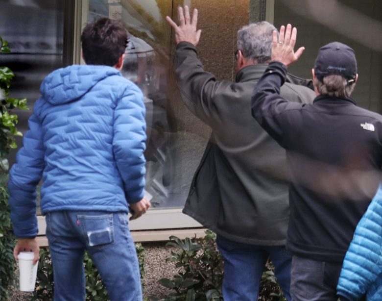 Family members wave to  Chuck Sedlacek, 87, a Life Care Center of Kirkland patient who tested positive for COVID-19 on March 8, after his family pushed for it, said his son-in-law, Clancy Devery. (Ken Lambert / The Seattle Times)