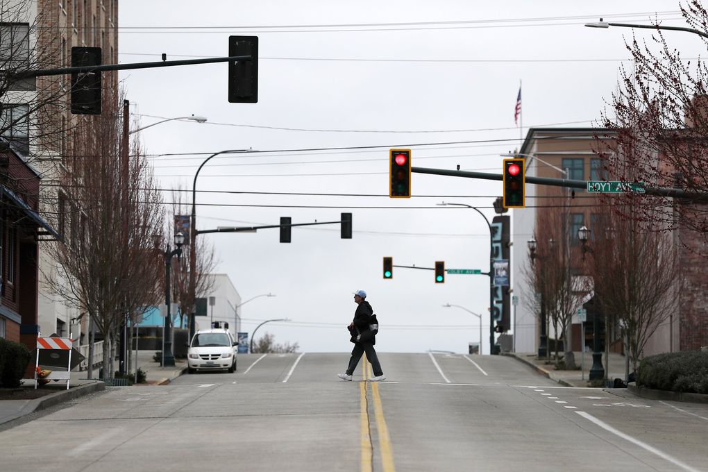 A man walks the quiet streets in downtown Everett on Saturday. Everett mayor Cassie Franklin issued an order for individuals to stay at home except for necessary errands, walks and caring for friends and relatives. The order takes effect at noon Monday. (Amanda Snyder / The Seattle Times)