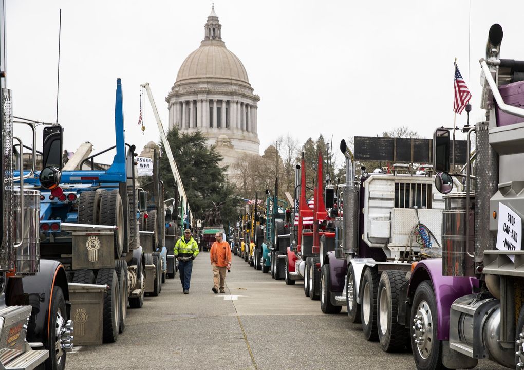 Brad Church, left, Jim Henke, right, and dozens of logging trucks align the street outside the Washington State Capitol building in Olympia on Monday, demonstrating against a low-carbon fuel-standard bill that many truckers worry would raise their fuel prices. (Amanda Snyder / The Seattle Times)