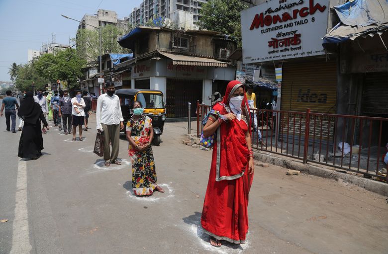 Indians stand in marked positions to buy essential commodities from a grocery store in Mumbai, India, Wednesday, March 25, 2020.The world’s largest democracy went under the world’s biggest lockdown Wednesday, with India’s 1.3 billion people ordered to stay home in a bid to stop the coronavirus pandemic from spreading and overwhelming its fragile health care system as it has done elsewhere. For most people, the new coronavirus causes mild or moderate symptoms, such as fever and cough that clear up in two to three weeks. For some, especially older adults and people with existing health problems, it can cause more severe illness, including pneumonia and death.(AP Photo/Rafiq Maqbool)