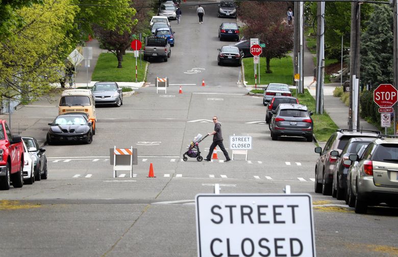 A pedestrian crosses East Columbia Street in the Central District, which is closed to through traffic to give people space to walk and bike.  (Ken Lambert / The Seattle Times)