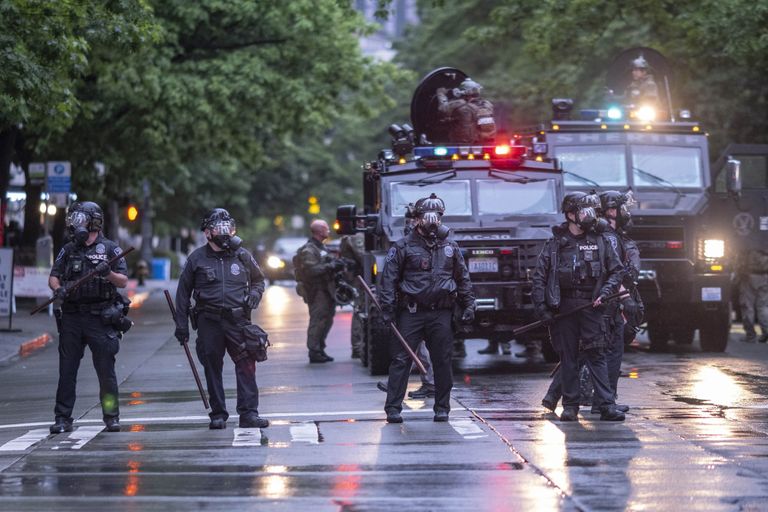 SWAT officers scatter protesters from Fourth Avenue downtown on Saturday. The protests were sparked by the killing of George Floyd, a Black man who died after being pinned to the ground by the knee of a Minneapolis police officer for several minutes. (Dean Rutz / The Seattle Times) 