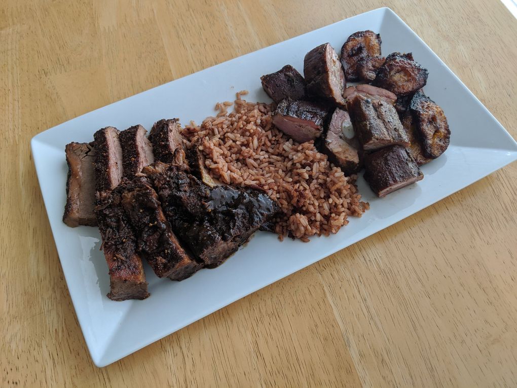 Don’t miss the jerk barbecue sauce and brisket from Lil Red Takeout and Catering, shown here with rice and beans, pork rib tips and wonderful caramelized plantains. (Jackie Varriano / The Seattle Times)
