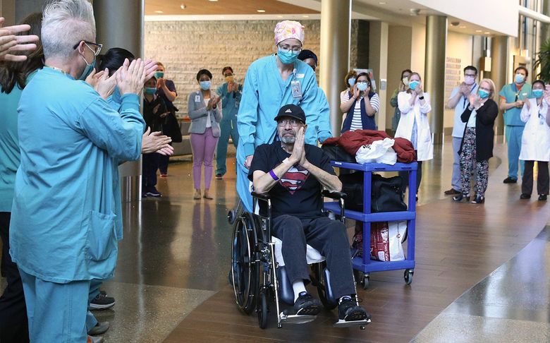 Health care workers applaud Michael Flor upon his release from Swedish Issaquah last month Pushing the wheelchair is Dr. Anne Lipke, Flor’s critical care doctor. (Ken Lambert / The Seattle Times)