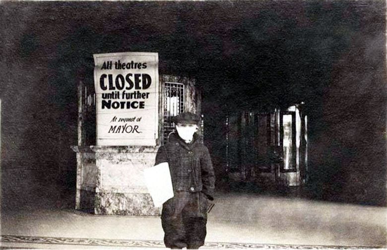 THEN: A masked newsboy looks west outside the closed Pantages Theatre box office during the influenza pandemic of nearly 102 years ago. Likely, the photo was taken between Oct. 5 and Nov. 11, 1918. Seattle theater historians helped us identify the Pantages by matching the marble pattern in its box-office base with that in a later photo. (Courtesy Museum of History & Industry) 