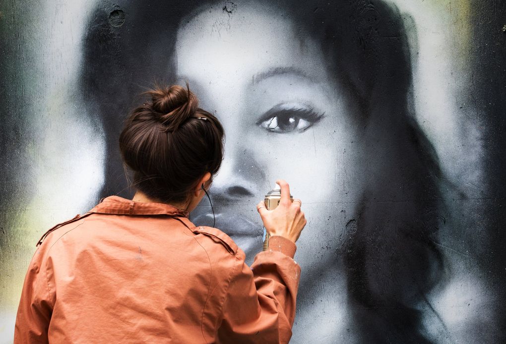 Seattle artist Mari Shibuya paints a portrait of Breonna Taylor, a 26-year-old emergency medcial technician who was killed when shot at least eight times in her apartment by Louisville, Kentucky police in March. Mari said she is painting the portrait to bring visibility to Breonna’s memory and her story. The mural is on a piece of plywood covering a window of Eastern Cafe in Seattle’s Chinatown International District. The cafe is still open for business. (Ellen M. Banner / The Seattle Times)