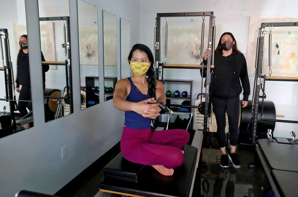 Jessica Notman, owner of Emerald City Pilates, right, works with Elena Cheung at the studio Thursday.  Notman lives in the neighborhood and has noticed the void without Amazon's usual crowd.  (Greg Gilbert / The Seattle Times)
