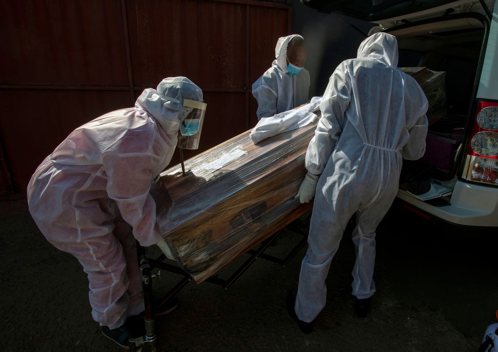 Funeral home workers in protective suits carry the coffin of a woman who died from COVID-19 into a hearse in Katlehong, near Johannesburg, South Africa, on Tuesday, July 21, 2020. South Africa last Saturday became one of the top five worst-hit countries in the coronavirus pandemic, as breathtaking new infection numbers around the world were a reminder that a return to normal life is still far from sight. (AP Photo/Themba Hadebe)