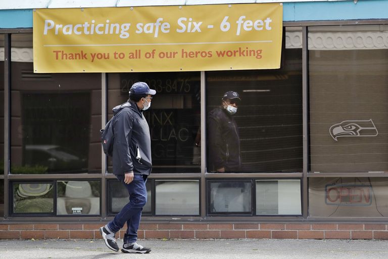 A man is reflected in the window of a closed Seattle business. Washingtonians filed 25,201 new claims for jobless benefits during the week ending Saturday — a 71.7% increase from the week before. (Elaine Thompson / The Associated Press 
