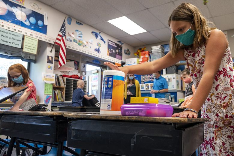 In Clarkston, Asotin County, Parkway Elementary School fourth-grader Joslyn Walkup prepares for the first day of class with a canister of disinfecting wipes on Aug. 26. In Washington state, officials have recorded at least 42 school outbreaks of coronavirus, with an outbreak defined as spread among two or more people, since the start of the pandemic.(Pete Caster / For The Seattle Times)