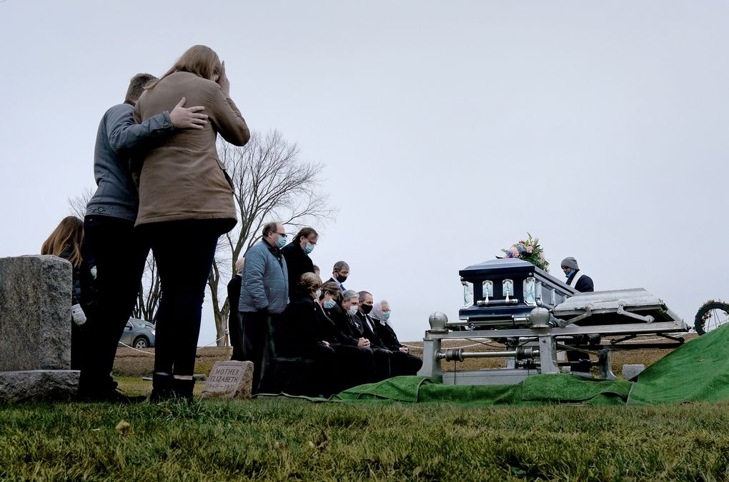 Dean Cynor, sitting, hands folded in center, attends the funeral for his mother at the Bohemian National Cemetery in Cadott, Wis., on Wednesday, Nov. 25, 2020. While he was being treated at the Mayo Clinic, his mother was admitted to the hospital two floors above him with what turned out to be a fatal case of COVID-19. (Washington Post photo by Michael S. Williamson)