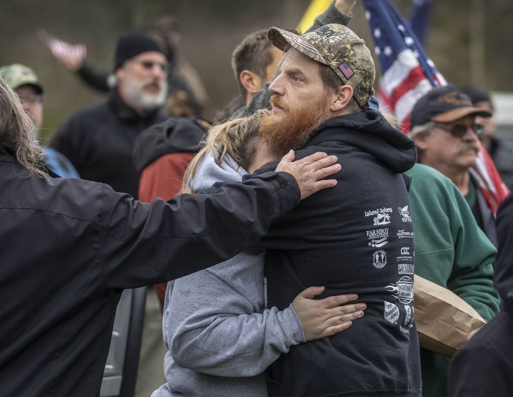 Brian Robbins, the owner of Farm Boy restaurant, is hugged by supporters after he gave an emotional speech to those gathered for a rally outside his restaurant protesting lockdowns for small businesses. (Steve Ringman / The Seattle Times)